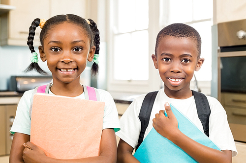 Cute siblings ready for school looking at the camera in the kitchen