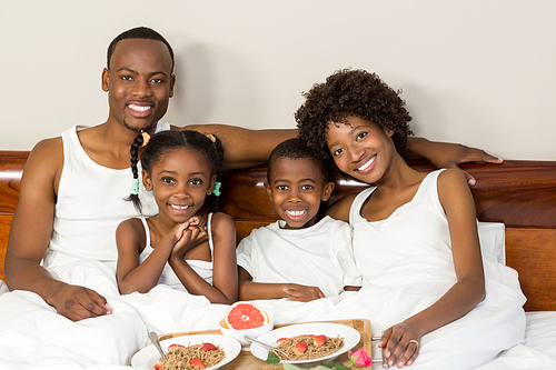 Happy family lying in bed together enjoying breakfast