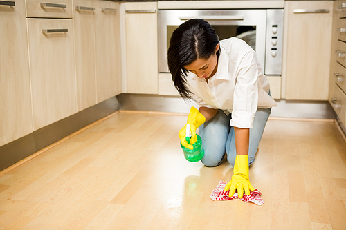 Attractive brunette cleaning the floor in the kitchen