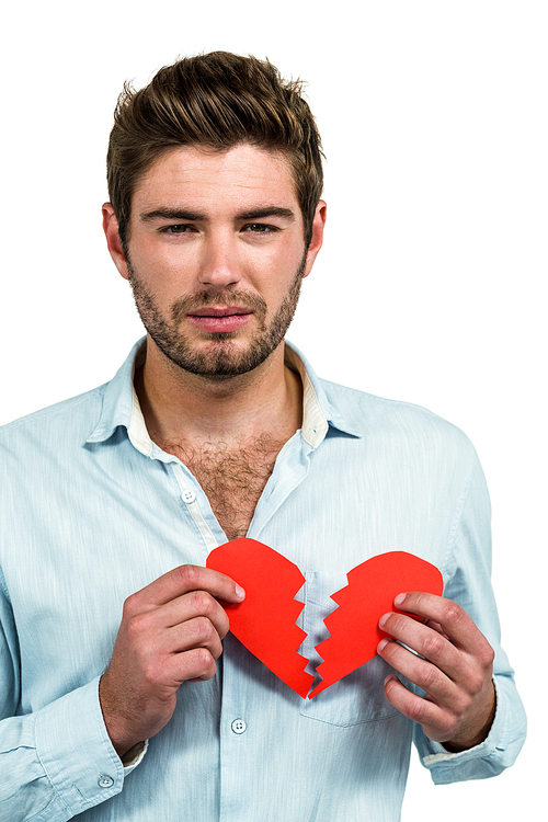 Sad man holding heart halves on white background