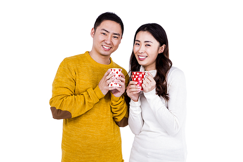 Portrait of happy young couple holding cups against white background