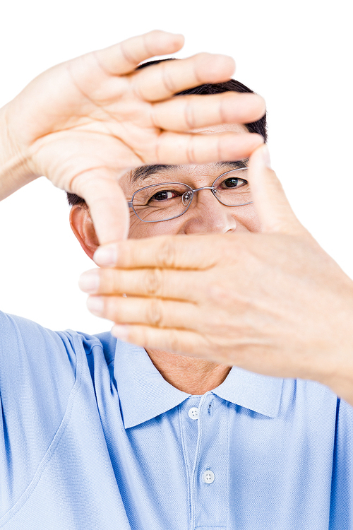 Portrait of man looking through hands against white background