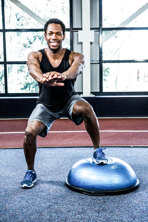 Fit man doing exercise with bosu ball in crossfit