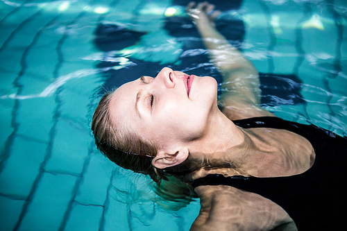 Relaxed woman floating in the swimming pool at leisure center