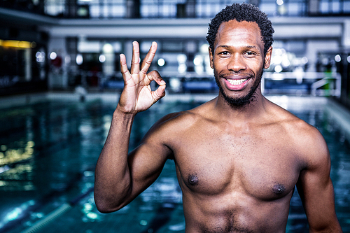 Fit swimmer gesturing ok sign in swimming pool