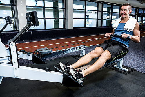 Muscular man using rowing machine at gym