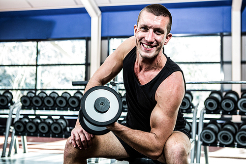 Muscular man exercising with dumbbells at gym