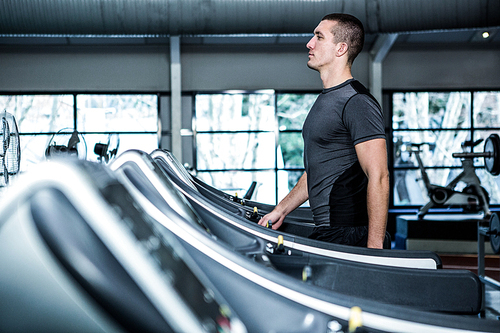 Concentrated muscular man using treadmill at gym