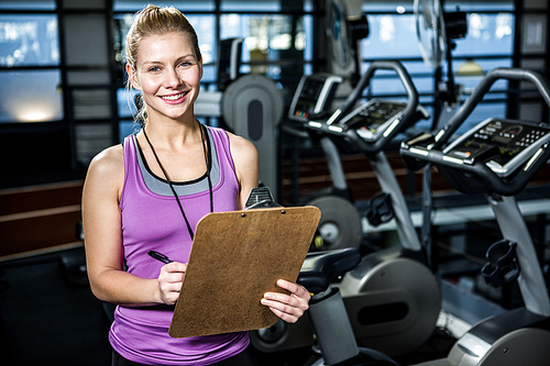 Smiling trainer holding clipboard at the gym