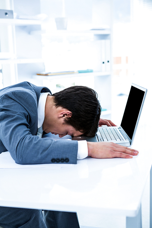 Businessman lying on his desk in office