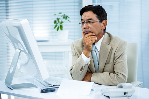 Undecided businessman at his computer in his office