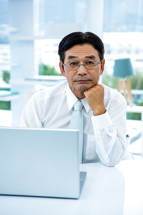 Thoughtful asian businessman looking at the camera in office