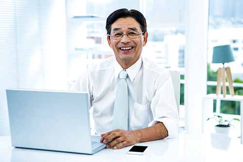 Smiling asian businessman working on laptop in office