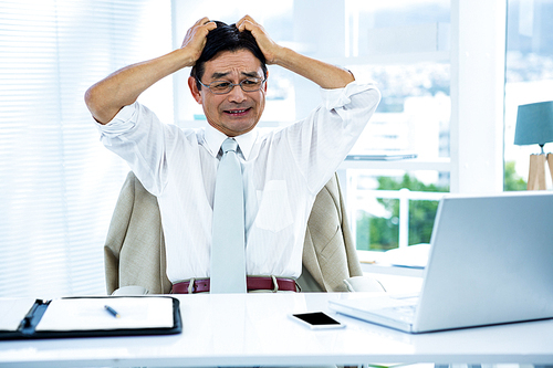 Overwhelmed asian businessman going crazy in office