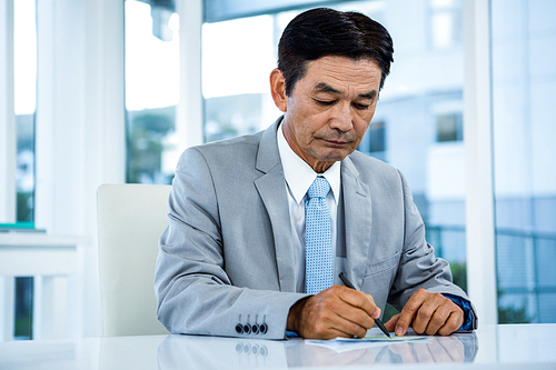 Businessman writing on paper in office