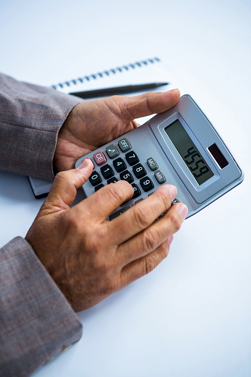 Businessman holding and using calculator in office