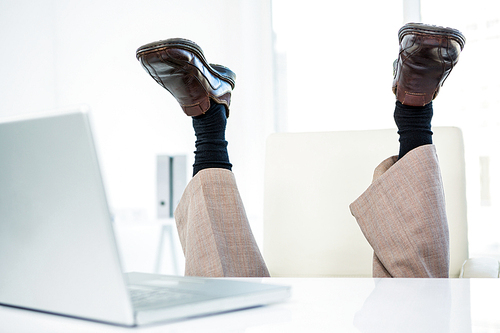 Businessman lying on the ground with feet up in office