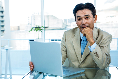 Smiling asian businessman working on laptop in office