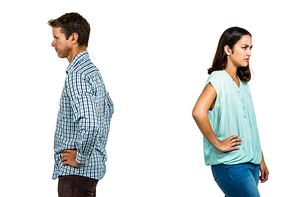 Frustrated couple ignoring each other while standing against white background