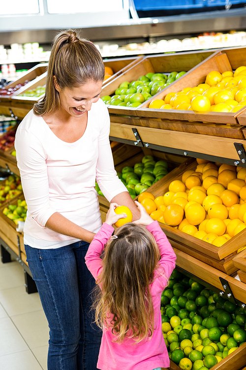 Mother and daughter taking fruit in grocery store