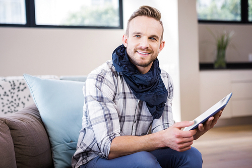 Handsome man using tablet on the couch in the living room