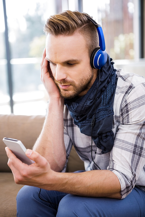 Handsome man listening music on the couch in the living room