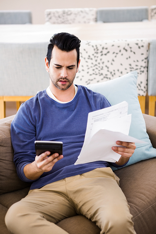 Handsome man counting bills on the sofa