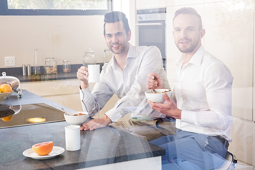 Smiling gay couple having breakfastin the kitchen