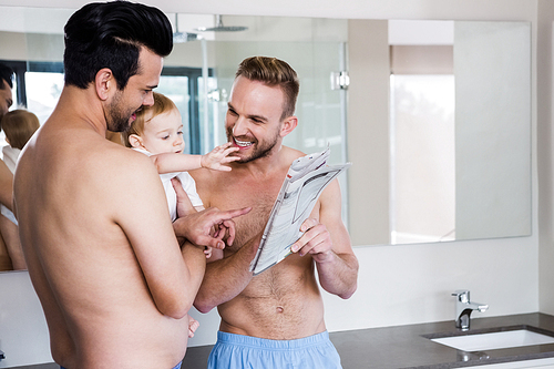 Smiling gay couple with child at home