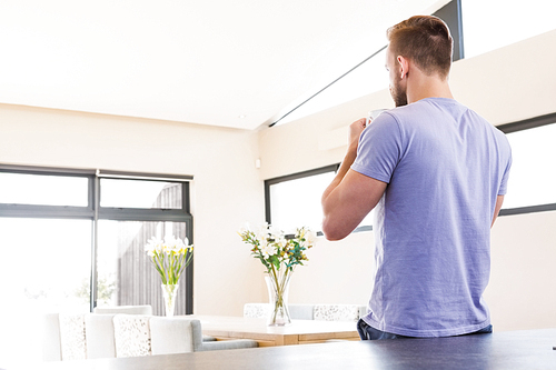 Rear view of handsome man drinking coffee in the living room