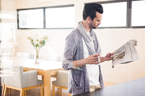 Handsome man reading newspaper in the living room