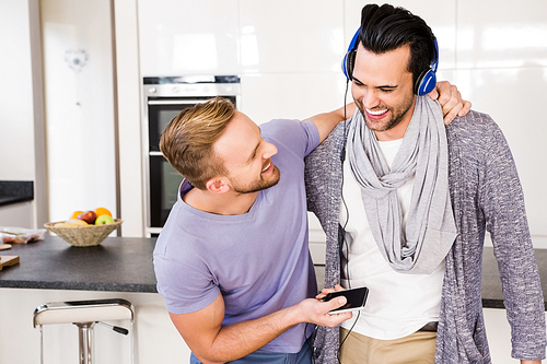 Smiling gay couple listening to music in the kitchen