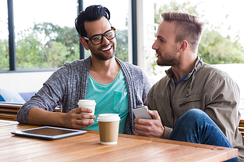 Designers with take-away coffee using smartphone at the office