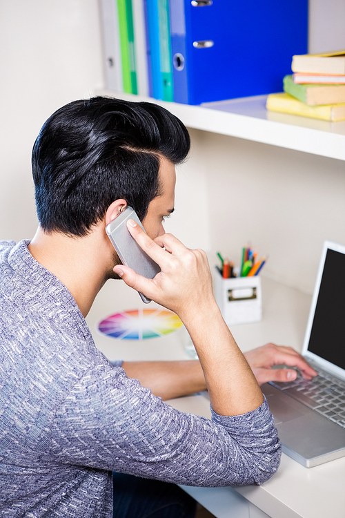 Busy man using smartphone and laptop at home