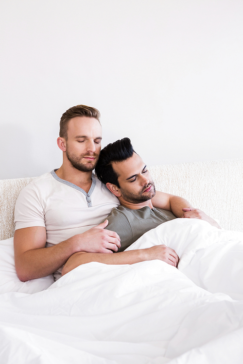 Asleep gay couple lying in bed at home