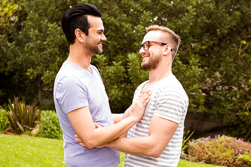 Smiling gay couple hugging in garden