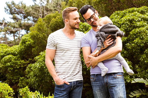 Smiling gay couple with child in garden