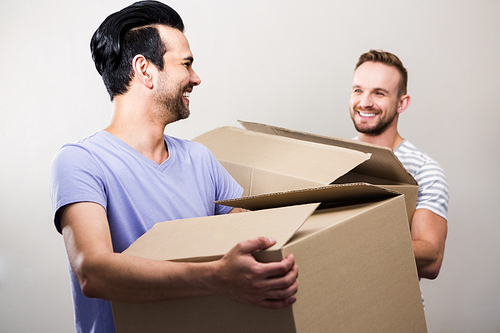 Happy gay couple holding boxes at new home