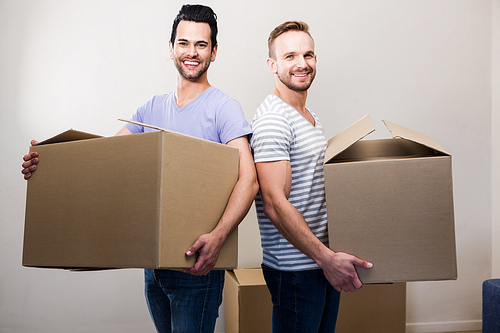 Happy gay couple holding boxes at new home