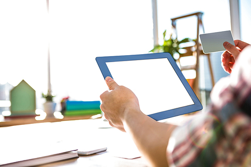 Cropped image of hipster businessman using tablet and credit card in office