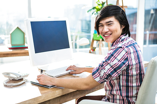 Smiling hipster businessman using computer in office