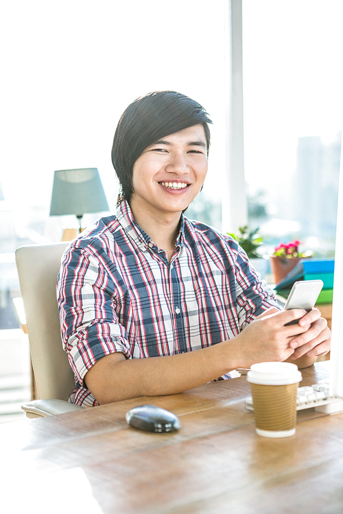 Smiling hipster businessman using smartphone in office