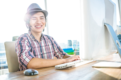 Smiling hipster businessman using computer  in office