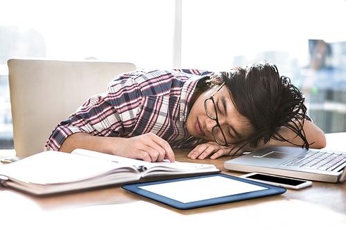 Hipster businessman falling asleep on desk in office