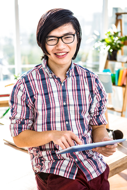 Smiling hipster businessman using tablet in office