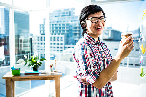 Smiling creative businessman with take-away coffee in office