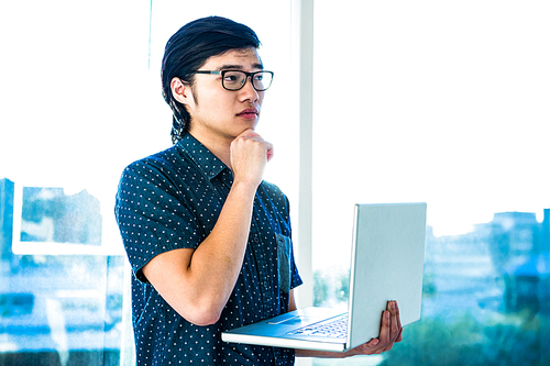 Thoughtful hipster using his laptop in office