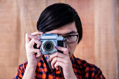 Hipster taking pictures with an old camera on wooden background