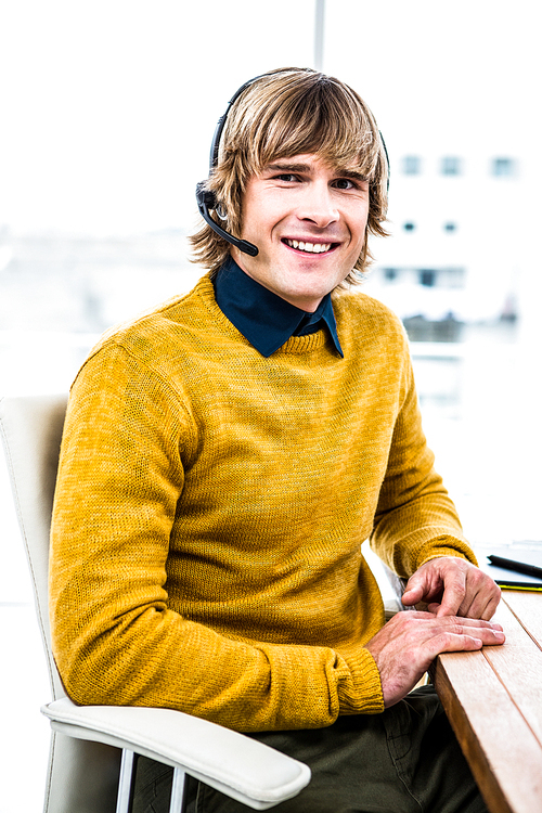 Smiling hipster businessman using headset in his office