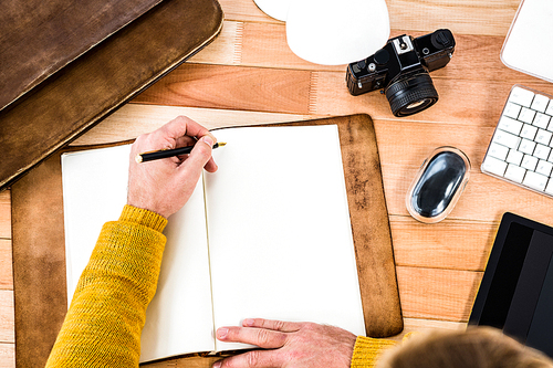 Above view of man writing on notebook on wooden desk